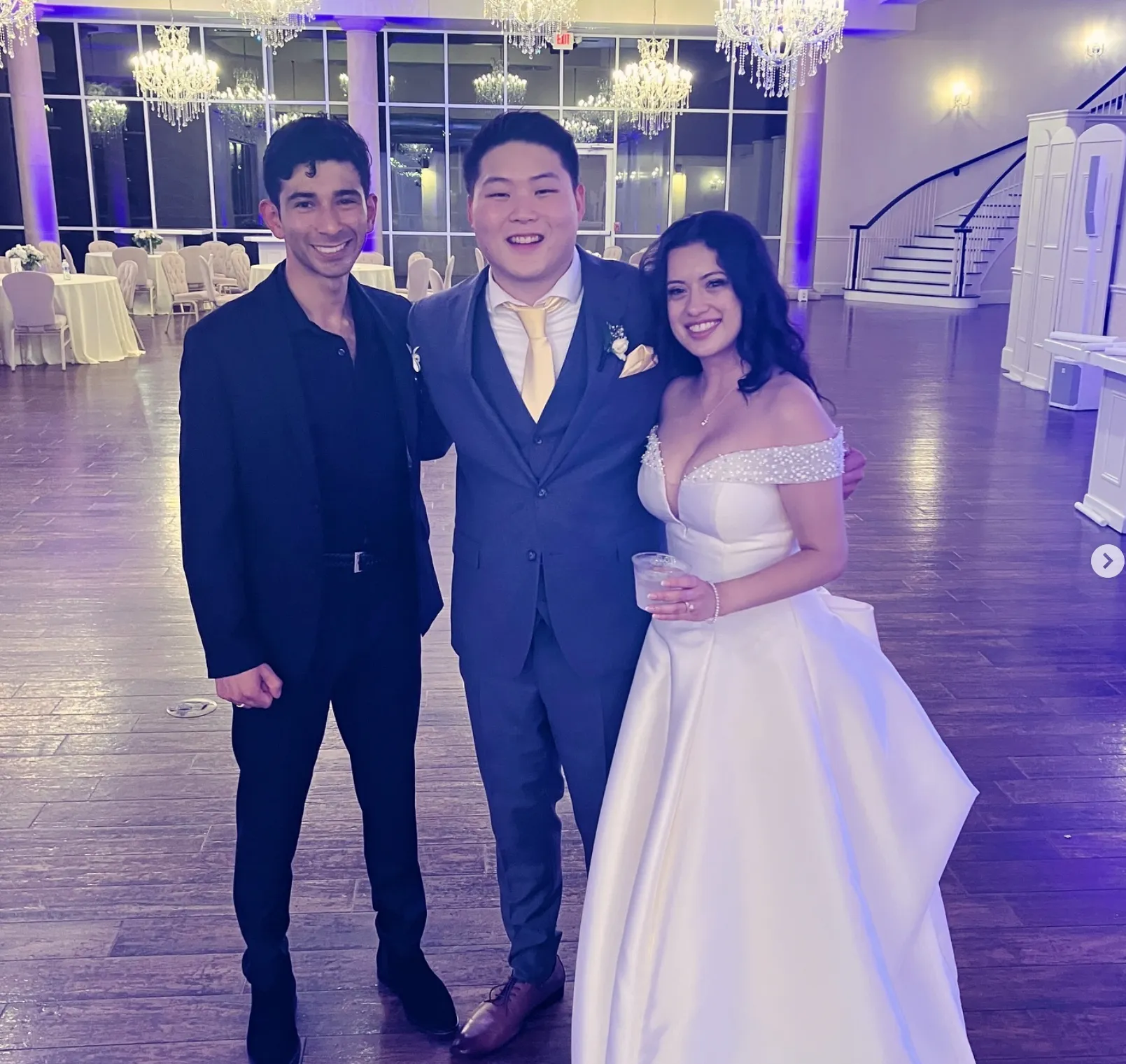 Michael Anthony with a newly married couple in a chandelier-lit ballroom
